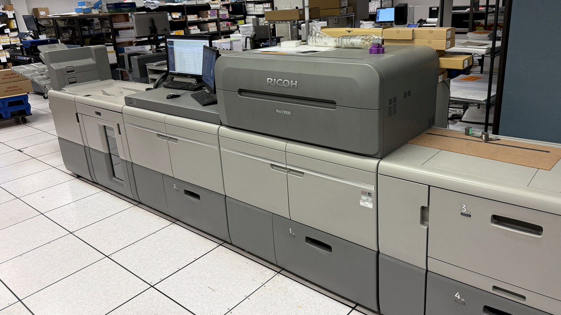 The Ricoh Pro C9500 digital press with its feeder and stacker units at Broudy Printing